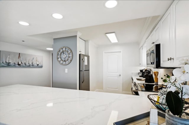 kitchen featuring stainless steel appliances, white cabinets, and light stone countertops