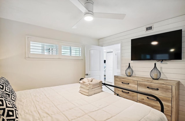 bedroom featuring ceiling fan and wood walls