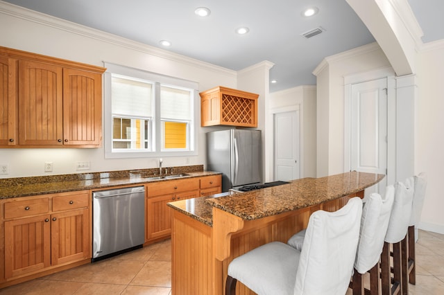 kitchen with a kitchen island, light tile patterned floors, appliances with stainless steel finishes, a breakfast bar, and dark stone countertops