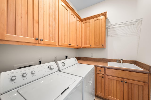 clothes washing area featuring cabinets, washer and clothes dryer, and sink