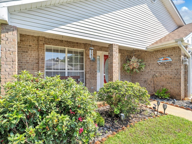 property entrance with brick siding and a shingled roof