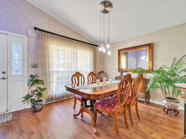 dining room with a textured ceiling, wood-type flooring, and lofted ceiling