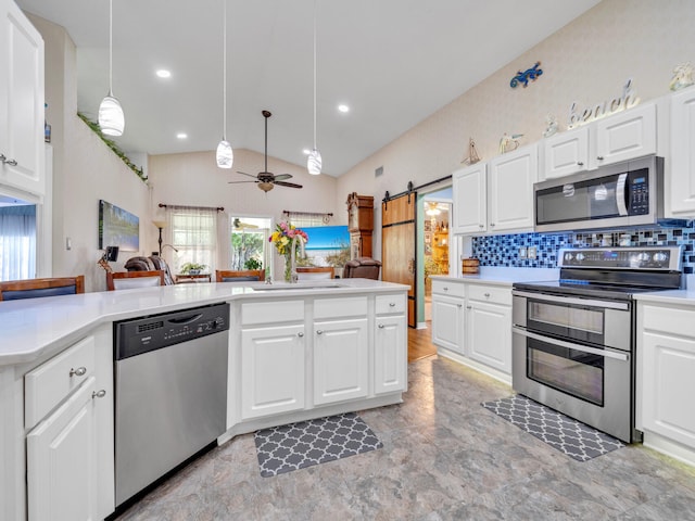 kitchen with white cabinets, a barn door, and appliances with stainless steel finishes