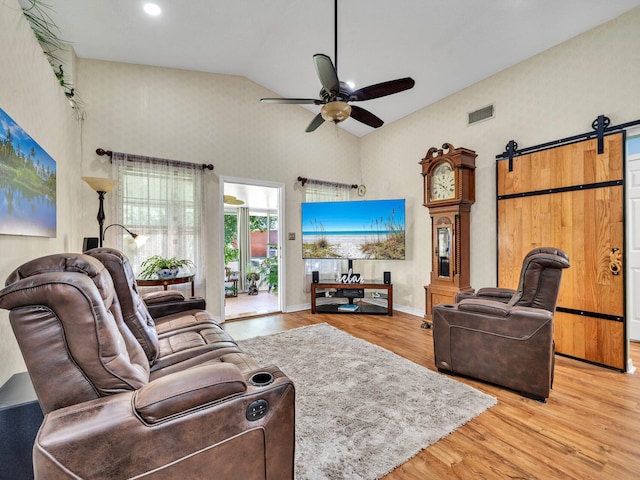 living room featuring a barn door, baseboards, visible vents, ceiling fan, and wood finished floors