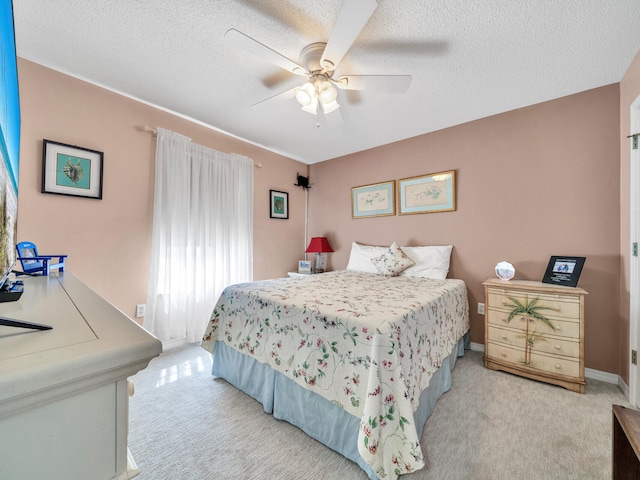 bedroom featuring light carpet, a textured ceiling, a ceiling fan, and baseboards