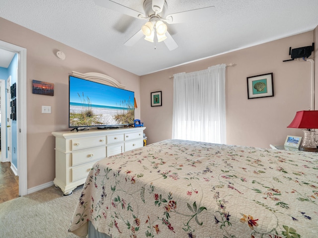 bedroom with a textured ceiling, baseboards, a ceiling fan, and light colored carpet