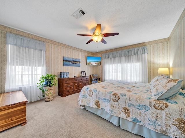 carpeted bedroom with multiple windows, ceiling fan, and a textured ceiling