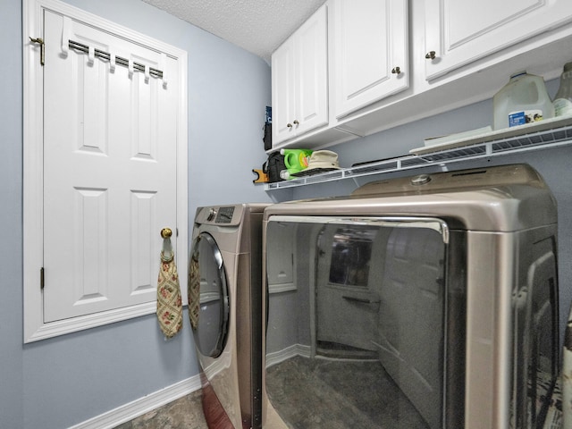 washroom featuring cabinet space, independent washer and dryer, a textured ceiling, and baseboards