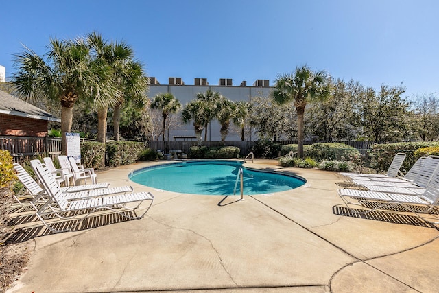 community pool with a patio area and fence