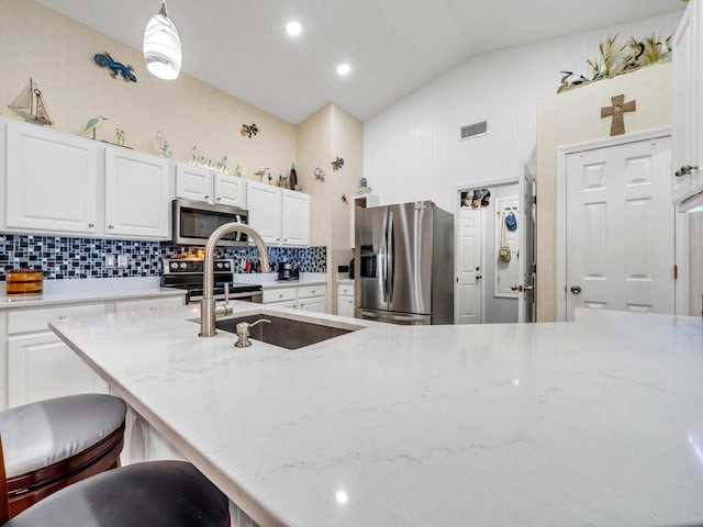 kitchen with stainless steel appliances, visible vents, a sink, and light stone countertops