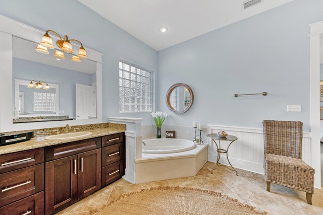 bathroom with tile patterned floors, a notable chandelier, a tub, and vanity