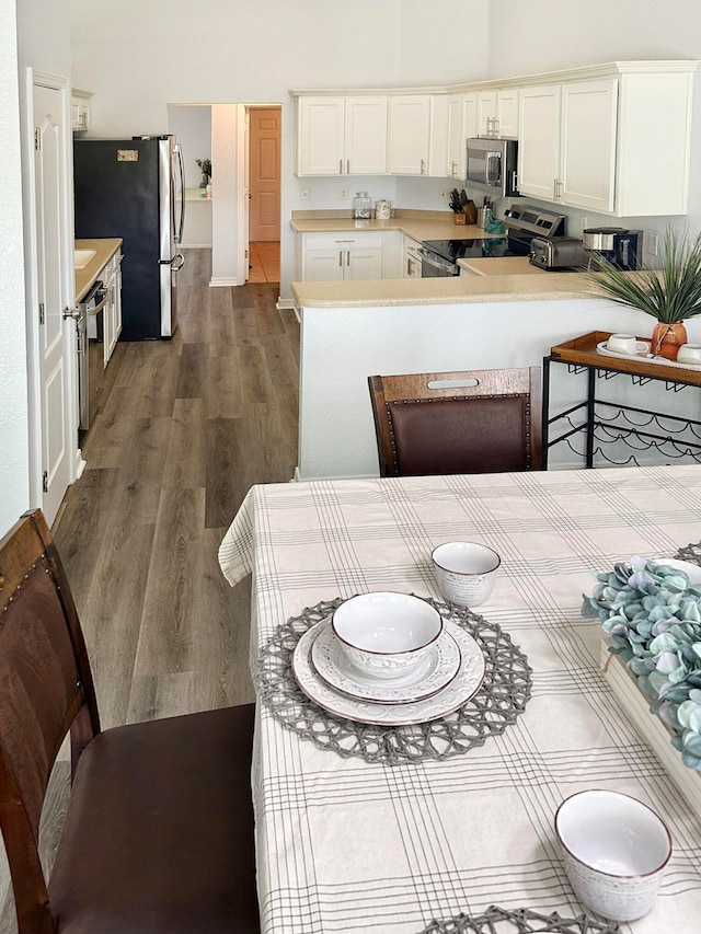 kitchen featuring white cabinetry, kitchen peninsula, appliances with stainless steel finishes, and dark wood-type flooring