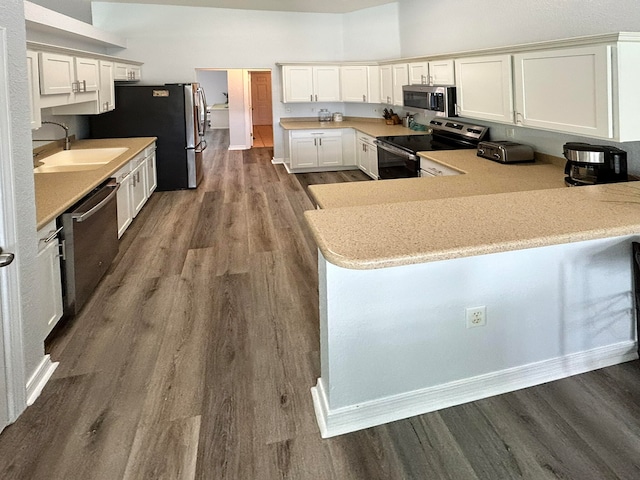 kitchen featuring appliances with stainless steel finishes, hardwood / wood-style flooring, kitchen peninsula, and sink