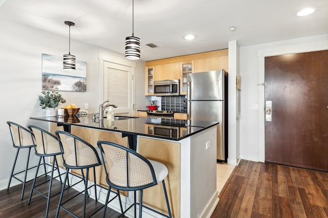 kitchen with sink, a kitchen breakfast bar, appliances with stainless steel finishes, and dark hardwood / wood-style floors