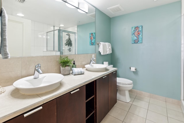 bathroom featuring decorative backsplash, a shower with door, toilet, vanity, and tile patterned floors