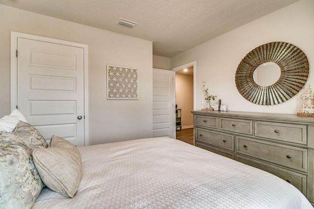 bedroom featuring visible vents, a textured ceiling, and wood finished floors