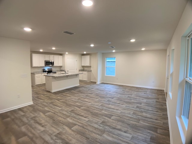 kitchen featuring a center island with sink, visible vents, appliances with stainless steel finishes, open floor plan, and white cabinetry