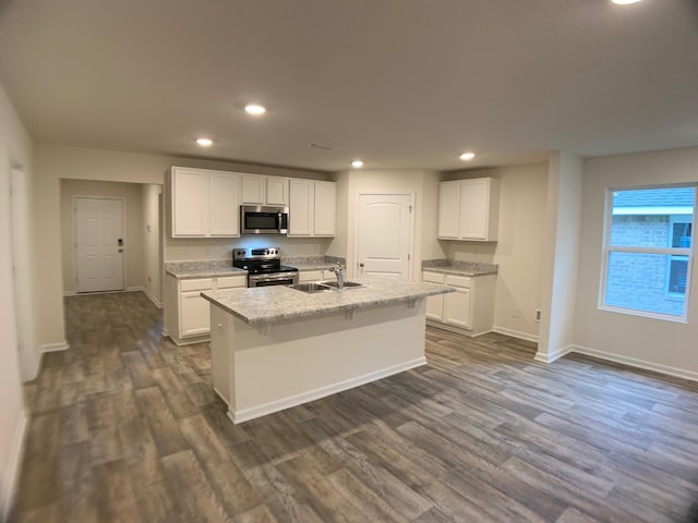 kitchen with appliances with stainless steel finishes, white cabinets, a sink, and an island with sink