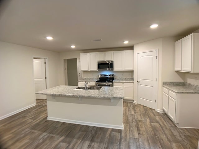 kitchen featuring dark wood finished floors, stainless steel appliances, a kitchen island with sink, white cabinets, and a sink