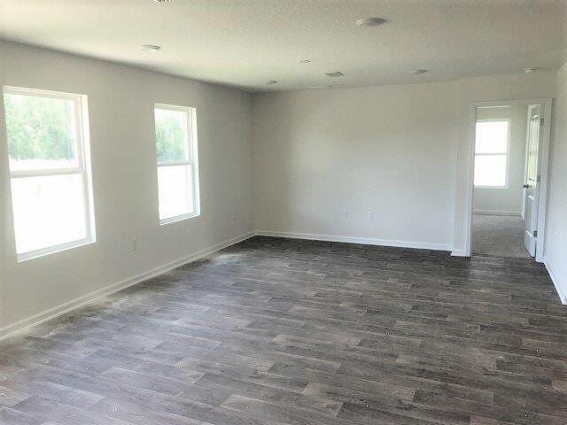 spare room with baseboards and dark wood-style flooring