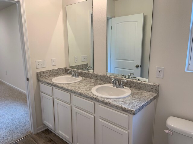 full bathroom with a sink, toilet, and double vanity