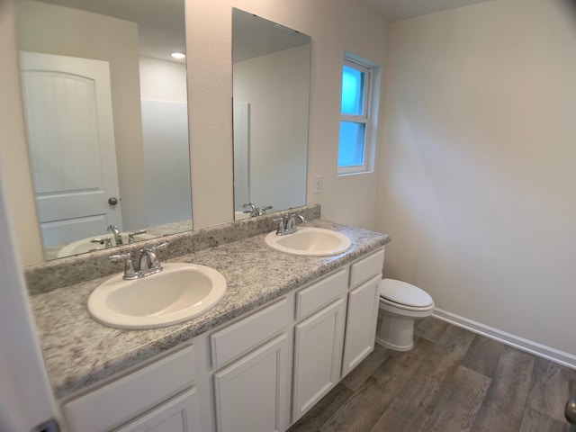 full bath with double vanity, a sink, and wood finished floors