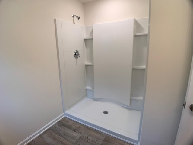 full bathroom with a stall shower, baseboards, and wood finished floors