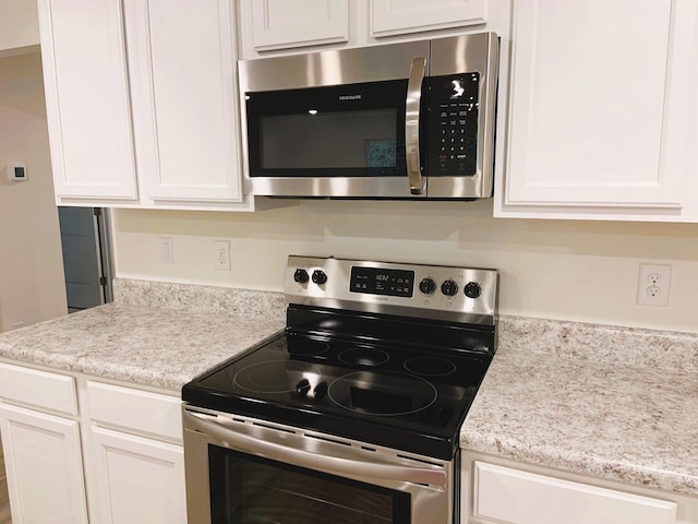 kitchen featuring white cabinetry, stainless steel appliances, and light stone counters