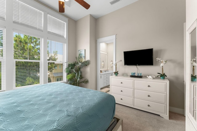 bedroom with ceiling fan, ensuite bath, visible vents, and light colored carpet