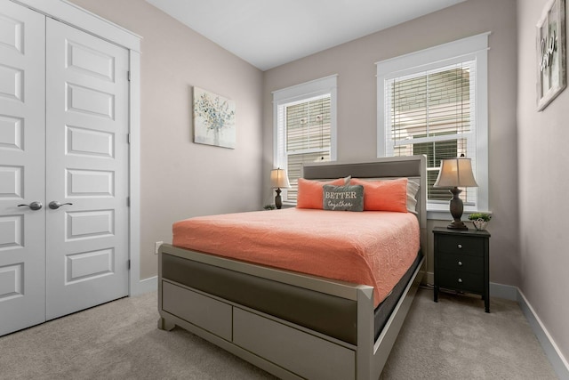 bedroom with baseboards, a closet, and light colored carpet