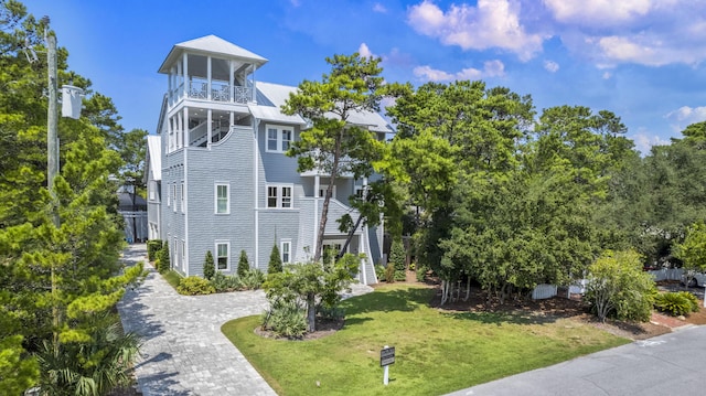 view of side of property featuring stairway, a balcony, decorative driveway, a lawn, and metal roof