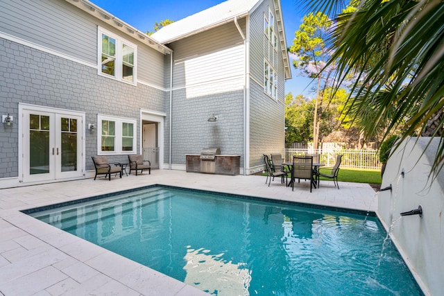 view of swimming pool with a patio, french doors, and pool water feature