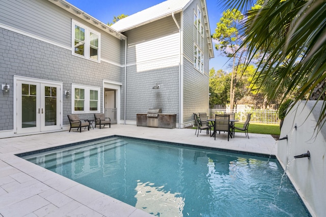 view of pool with a patio area, french doors, fence, a fenced in pool, and exterior kitchen