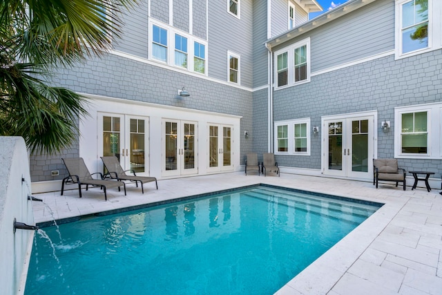 view of swimming pool featuring pool water feature, a patio area, and french doors