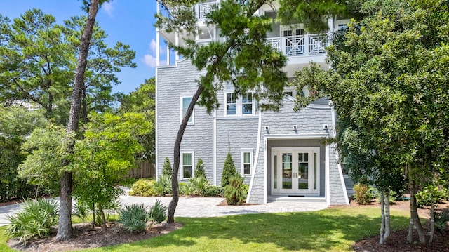 rear view of house featuring a balcony, french doors, and a yard