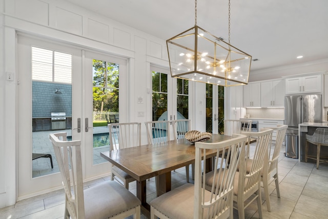 dining space featuring crown molding, french doors, a chandelier, and light tile patterned flooring