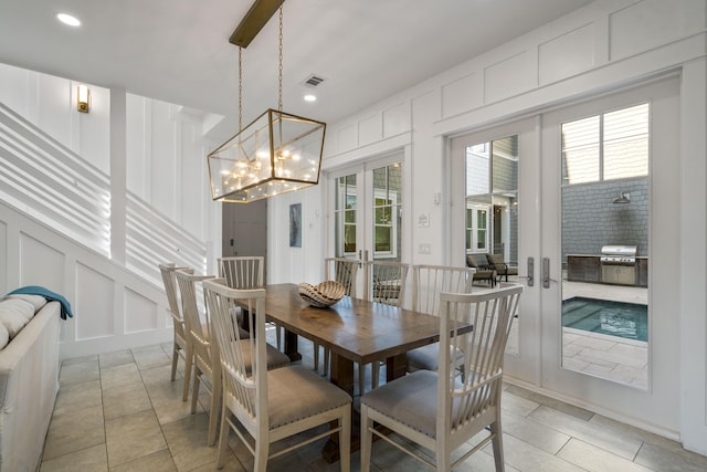 dining room with a decorative wall, plenty of natural light, a chandelier, french doors, and visible vents