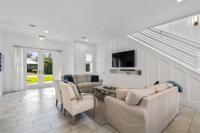living area with a decorative wall, french doors, visible vents, and recessed lighting