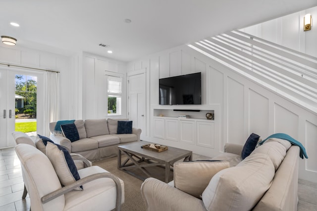 living area with recessed lighting, a decorative wall, and visible vents