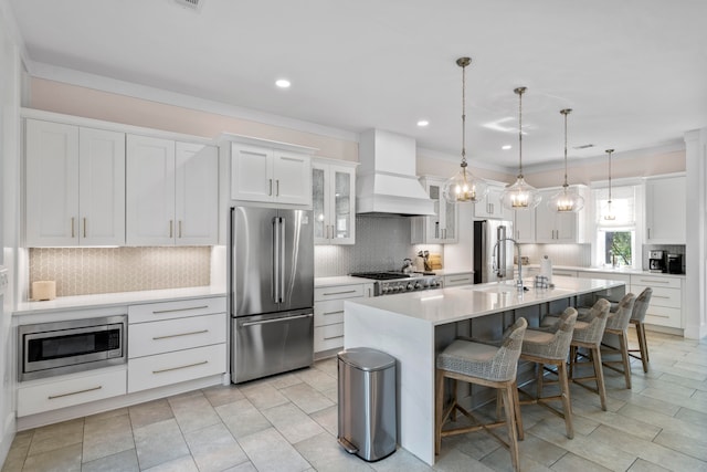 kitchen featuring backsplash, stainless steel appliances, sink, a kitchen island with sink, and custom exhaust hood