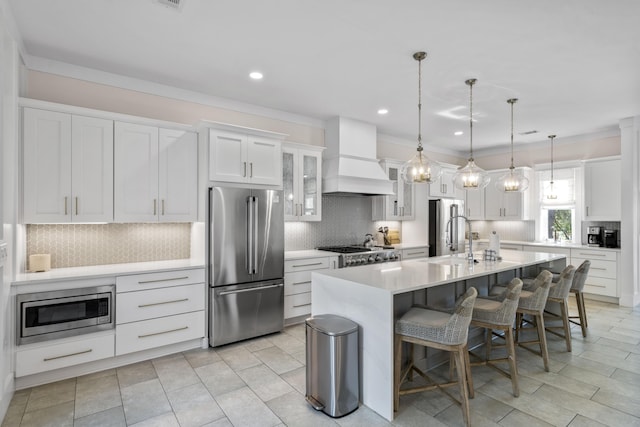kitchen featuring premium range hood, backsplash, appliances with stainless steel finishes, and a sink