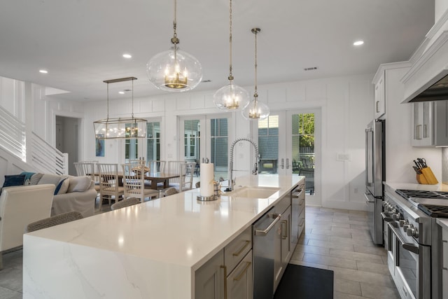 kitchen with stainless steel appliances, french doors, premium range hood, a sink, and a chandelier