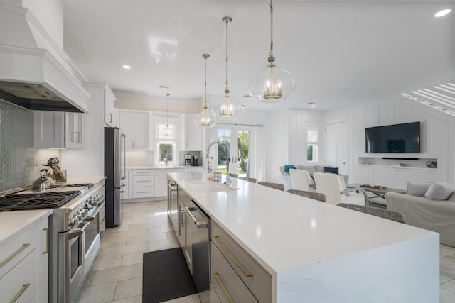 kitchen with stainless steel appliances, a sink, a spacious island, open floor plan, and custom exhaust hood