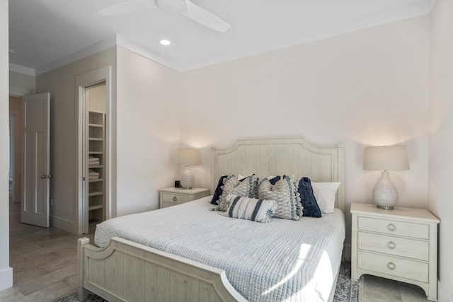 bedroom with wood finished floors, a walk in closet, ceiling fan, baseboards, and recessed lighting