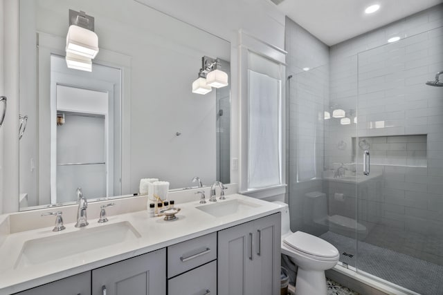 bathroom featuring double vanity, a shower stall, toilet, and a sink