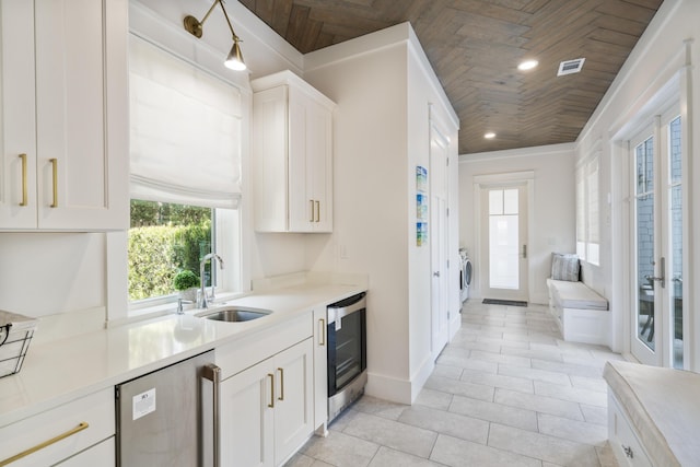 kitchen with white cabinets, a sink, baseboards, wood ceiling, and beverage cooler