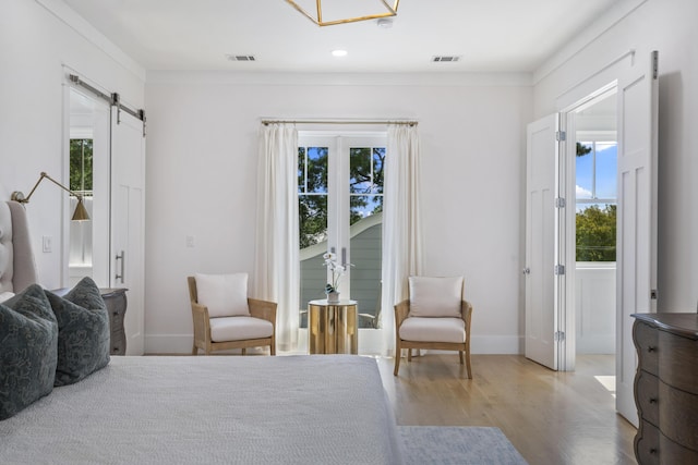 bedroom featuring a barn door, visible vents, and multiple windows