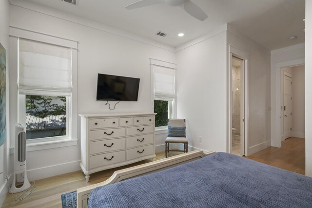 bedroom featuring light wood finished floors, ensuite bathroom, baseboards, visible vents, and ceiling fan