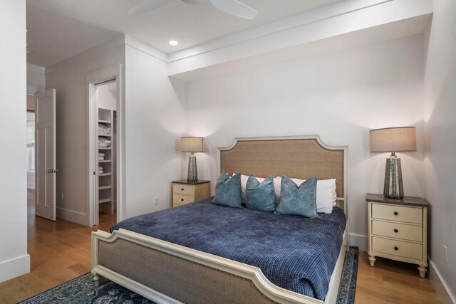 bedroom with ceiling fan, a spacious closet, and light hardwood / wood-style flooring