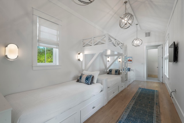 bedroom featuring lofted ceiling, a chandelier, ornamental molding, and light wood-type flooring